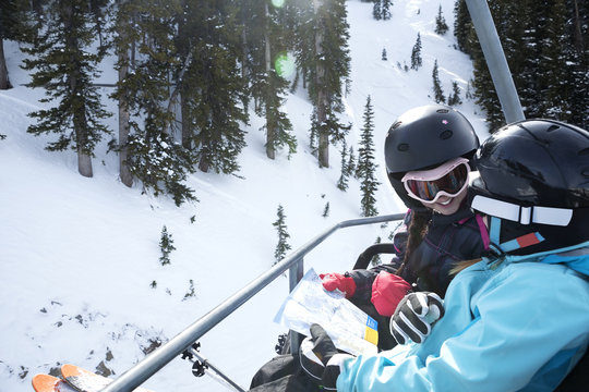 High angle view of girls reading map while riding on ski lift