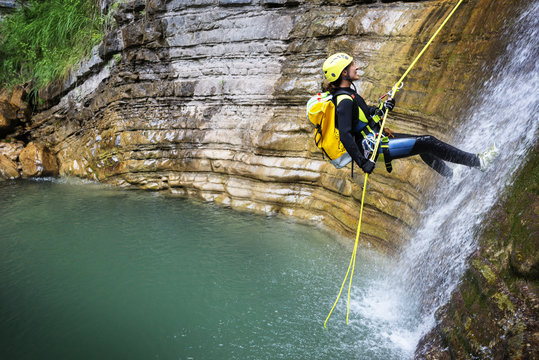 Side view of woman rappelling down into lake