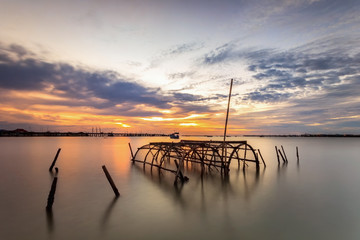 Fish trap made from wood and net in sea with sunset