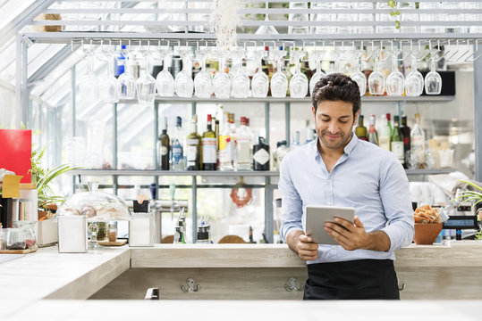 Bartender using tablet computer at counter in restaurant
