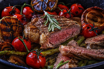 Steak with grilled vegetables in a frying pan.