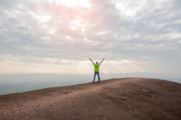 Man with arms outstretched on hill