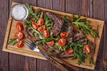Steaks with arugula and tomatoes.