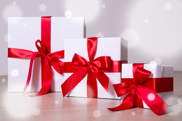 winter holiday concept - white gift boxes with red ribbon on woo