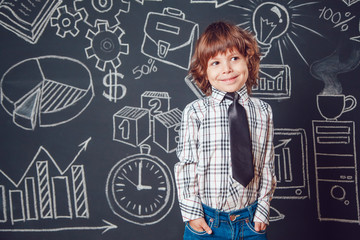 Little boy as businessman or teacher wearing shirt and tie on a dark background with business school picture