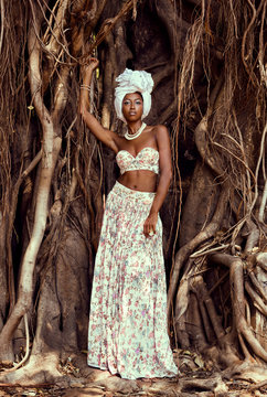 Woman in white headdress in front of tree trunk 