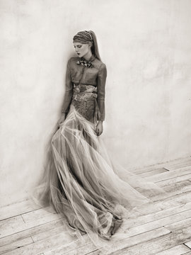 Woman wearing long tulle skirt, leaning against wall