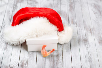 Obraz na płótnie Canvas Santa Claus hat over gift box on wooden background. Winter holidays concept. New Year of rooster.