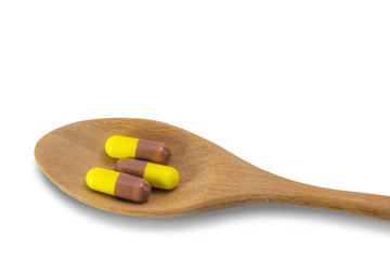 Capsule on a wooden spoon on white background with clipping path.