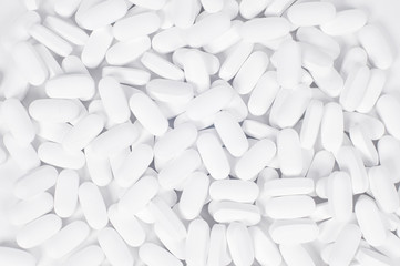 White pills on the white background.