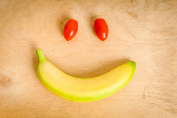 smile with banana and tomatoes lying on a wooden table