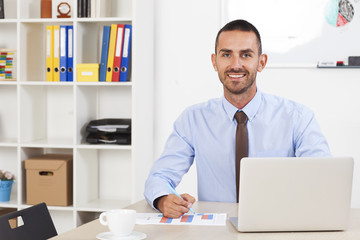 Happy businessman working in his office on the laptop