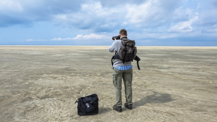 Fotograf mit Kamera und Ausr&uuml;stung in atemberaubender Landschaft (Nordsee)