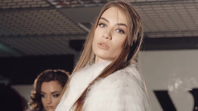Two rich models posing and catwalking in fur coats