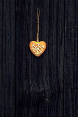 Gingerbread heart hanging on a dark wooden background