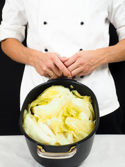 Chef in white jacket holding around a casserole of boiled cabbag