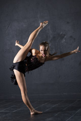 Plakat Young professional dancer make a twine against textured wall background