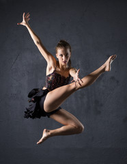 Fototapeta na wymiar Young professional dancer jumping against textured wall background
