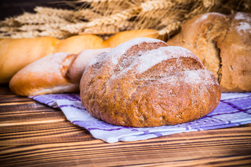 Assortment of baked bread on wooden table background