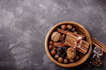 Spices and nuts in wooden bowl on dark background.