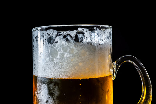 Glass of beer with foam isolated on black bacground