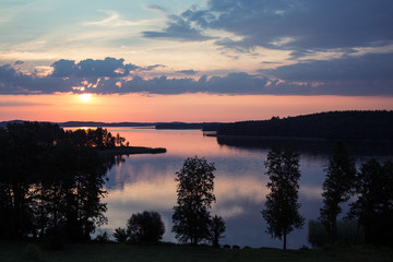 Sunset over the lake with islands with sky reflection in water