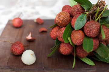 Lychee with leaves on a wooden board Copy space