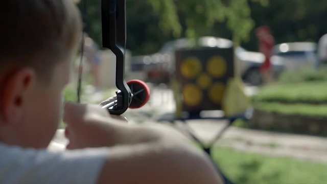 Little boy shoots bow in the park. Outdoors. Sport activities with children.