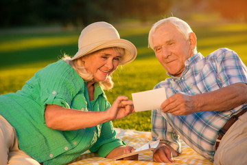 Senior couple looking at photographs. Smiling woman and man. How it all started. Glance into the past.