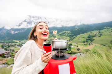 Young woman eating fondue a traditional swiss meal during a trip in the mountains in Switzerland