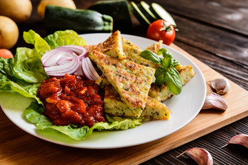 Fried savory zucchini pancakes, served with tomato salsa