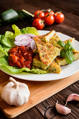 Fried savory zucchini pancakes, served with tomato salsa