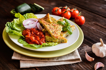 Fried savory zucchini pancakes, served with tomato salsa