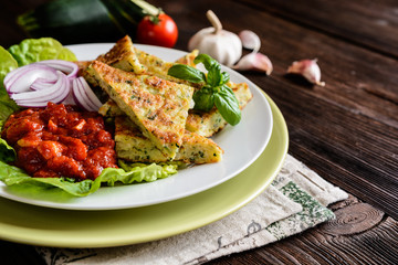 Fried savory zucchini pancakes, served with tomato salsa