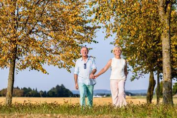 Senior Paar, Frau und Mann, beim Spaziergang über eine Wiese 