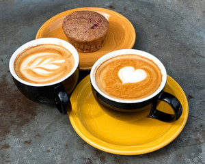 Art milk mocha coffee with foam and muffin on metal table