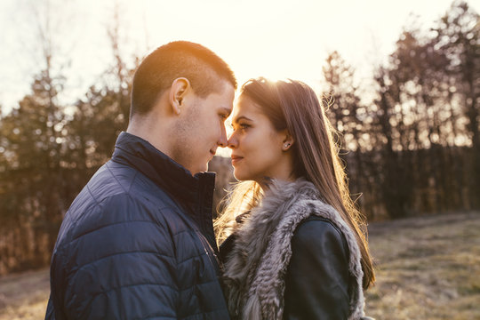 Beautiful teenager couple hugging and kissing. They enjoy autumn nature outdoors. Warm sunlight, flare and strong back light.