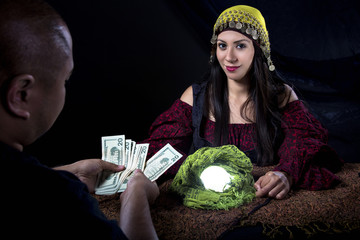 Female fortune teller psychic or con artist swindling money from a gullible male customer via fraud