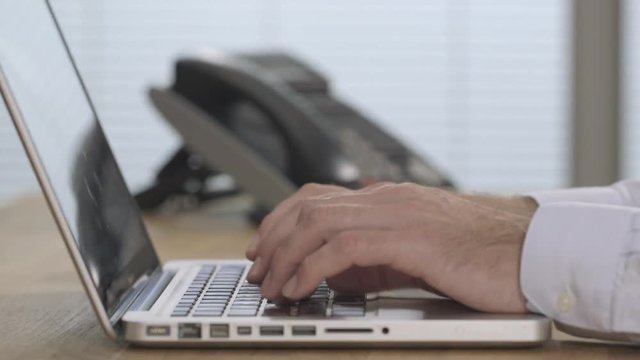 Male hands answering phone and typing in a modern office