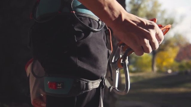 Slowmotion of male climber attaching carabiners on safety belt. Mountaineer or rock climbing holding a carabiner for his ropes in a close up view of the equipment in a healthy active lifestyle concept
