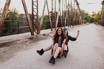 Two teens sit on one skateboard and laughing