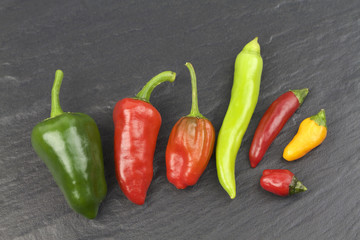  Various hot chili peppers on black stone background