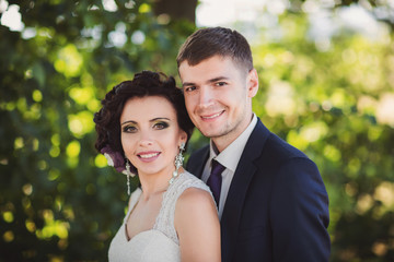 Wedding portrait. Elegant groom and beautiful bride with colorful makeup looking at the camera and smiling