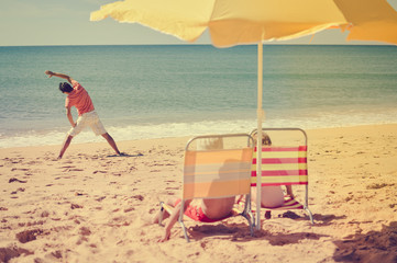 Joyful family having fun on beach sunny outdoors background. Back view