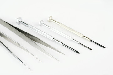 tweezers and screwdrivers on white background