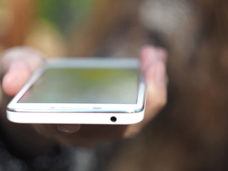 A young girl is using smartphone outdoors. Close-up