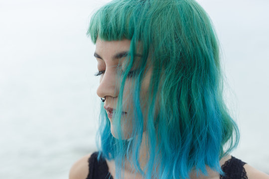 Headshot of sad blue haired girl looking away .