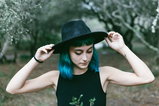 Pretty girl with short dyed hair toughing her hat.