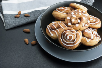 Twisted buns with cinnamon and icing sugar on a black background