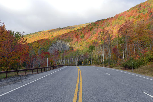 Fototapeta Driving into the mountains with Autumn foliage with red, orange and yellow fall colors in A Northeast forest